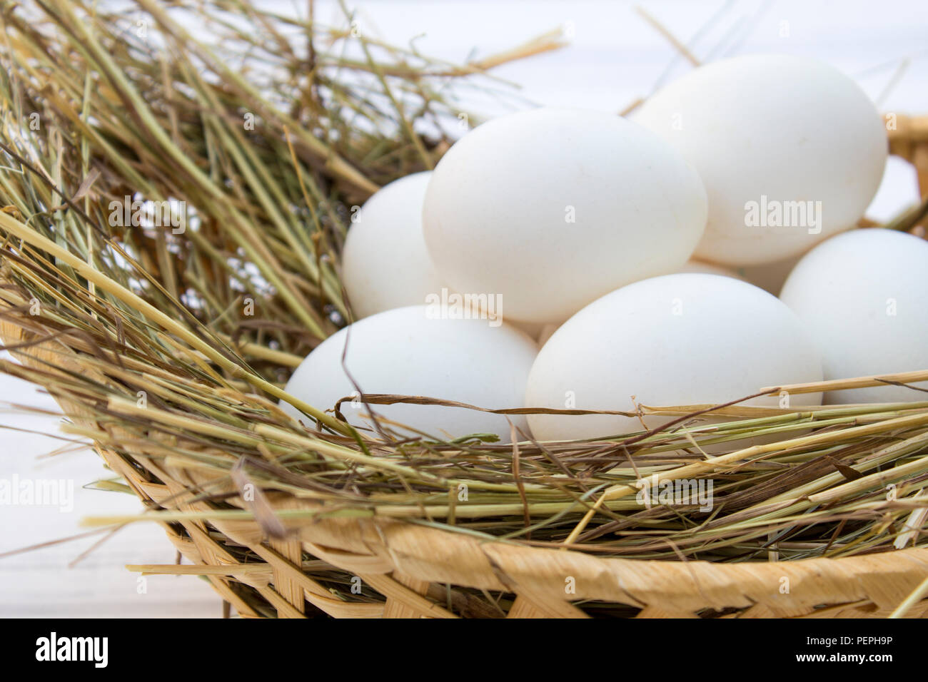 chicken eggs in basket with hay on a white wooden background. eggs on ...