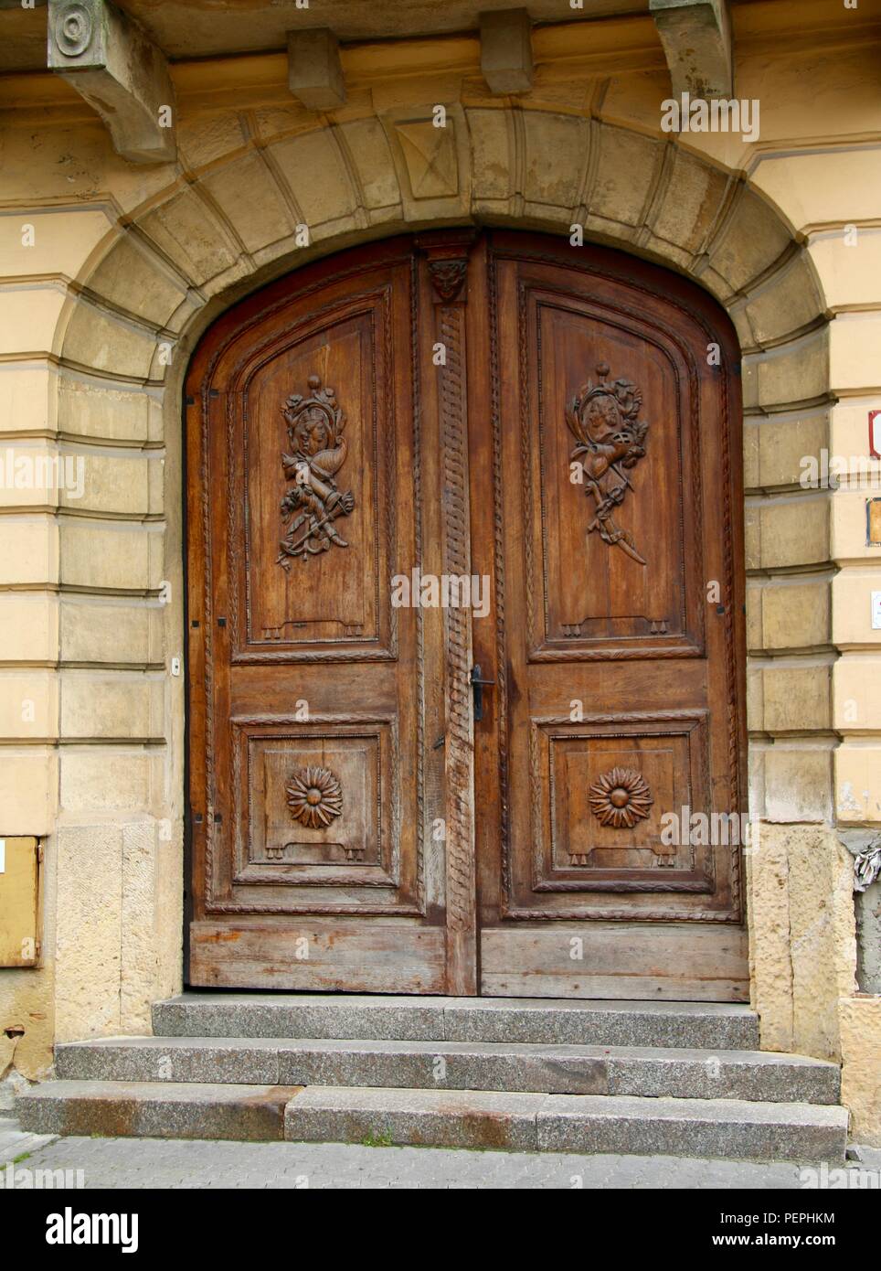 Double wooden doors carved with protection faces at the top to stop the evil eye in Europe Stock Photo