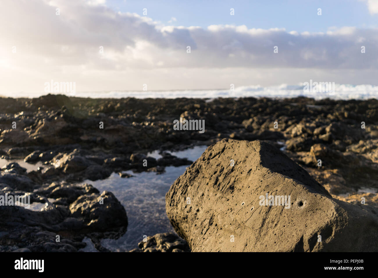 Sun shining on black volcanic rock beach on Lanzarote Island Stock Photo