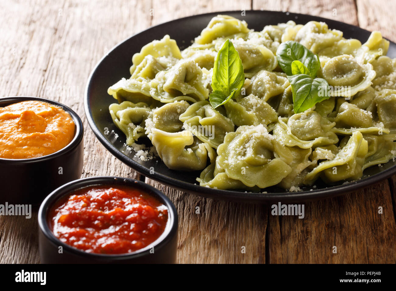 Tasty spinach green cappelletti, ravioli, tortellini with cheese, basil, ketchup, mustard close-up on the table. horizontal Stock Photo