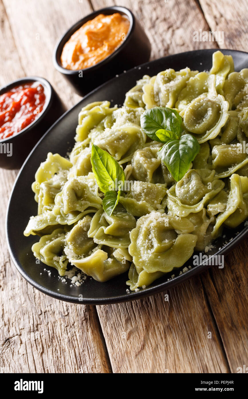 Spinach cappelletti, ravioli, tortellini stuffed with meat with Parmesan cheese and basil served with sauces close-up on the table. vertical Stock Photo