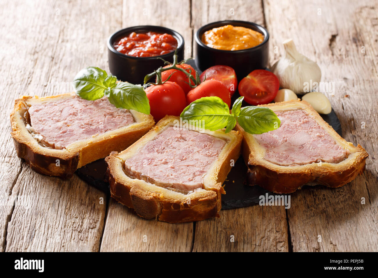 Spicy French pork terrine with brioche, vegetables and sauces closeup