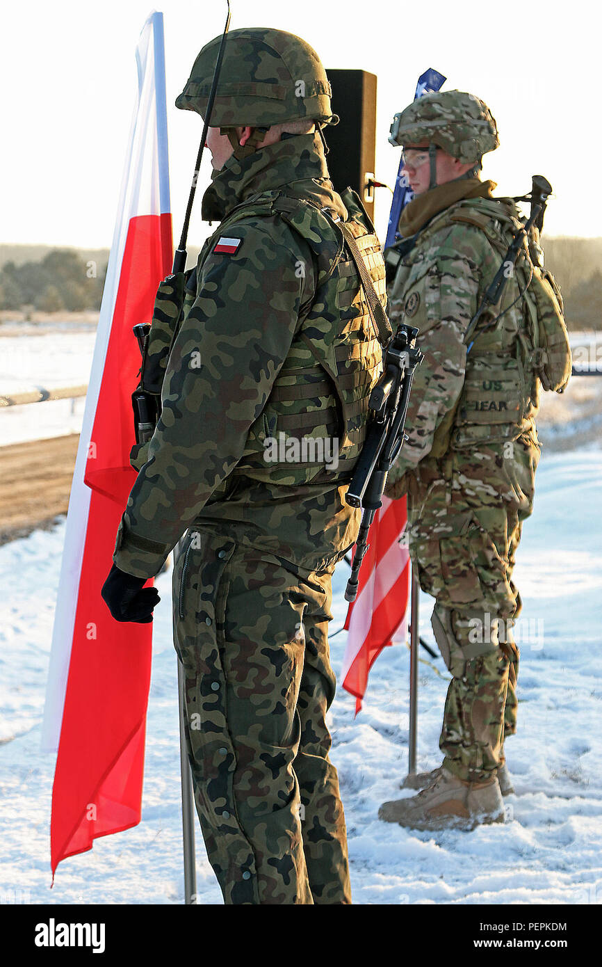 A Polish and American soldier stand side by side bearing their country's  colors before an opening of training ceremony recognizing the partnership  between the two nations participating units, K Troop, 3rd Squadron,