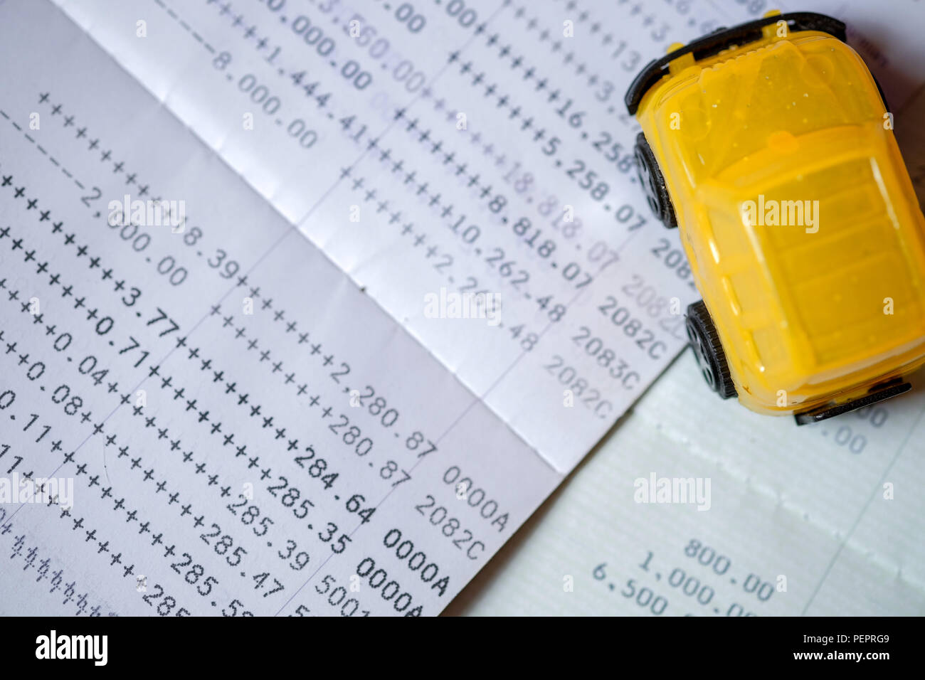 Yellow toy car placed on a bank passbook on top-view, with concept to pay in installments. In order to buy car, Stock Photo