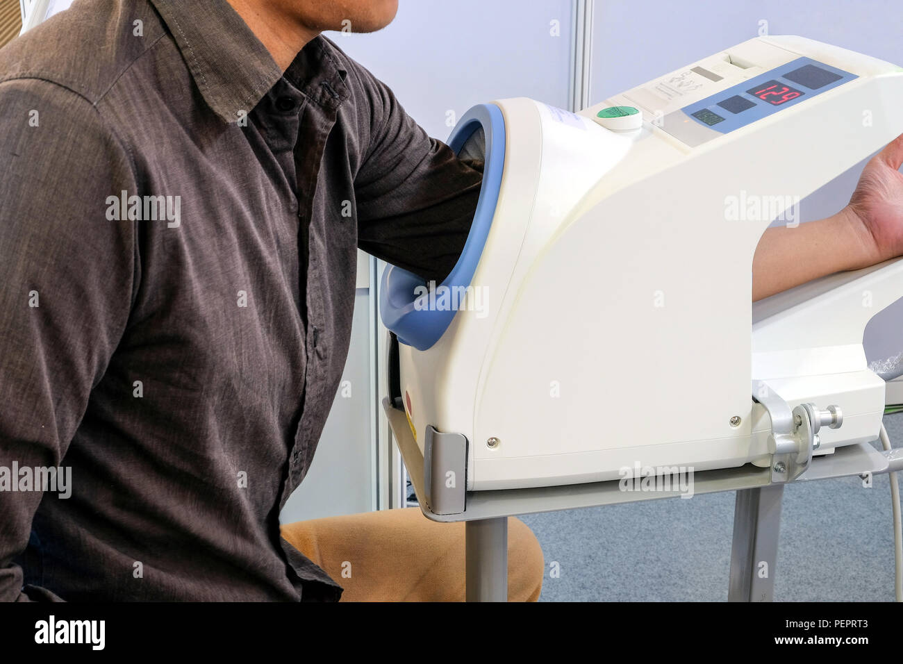 Male patients insert their left arm into the pressure monitor. To check the blood pressure and heart rate. Stock Photo