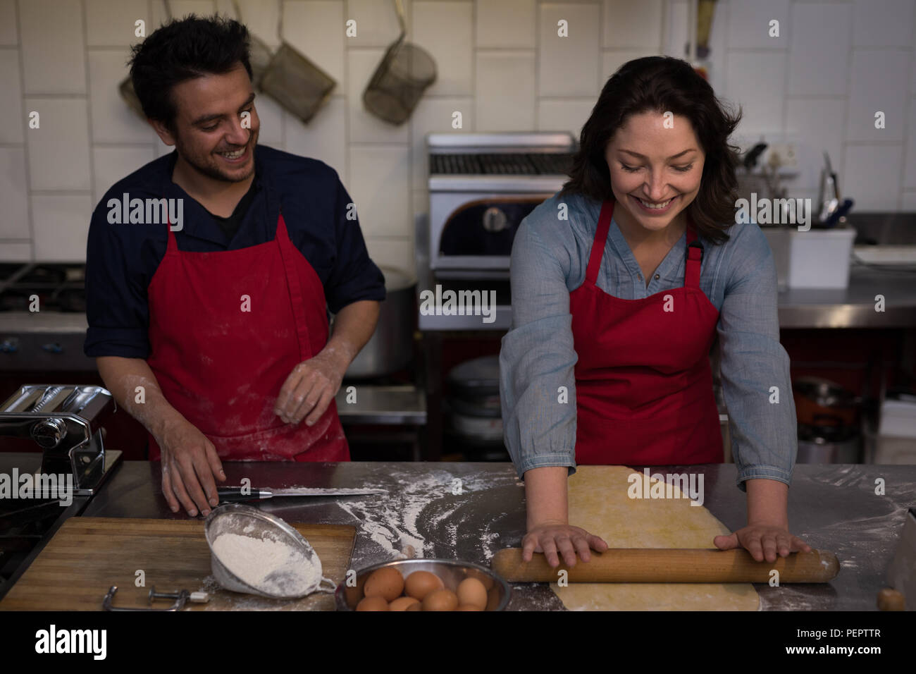 Female Baker rolling a dough for making pasta Stock Photo