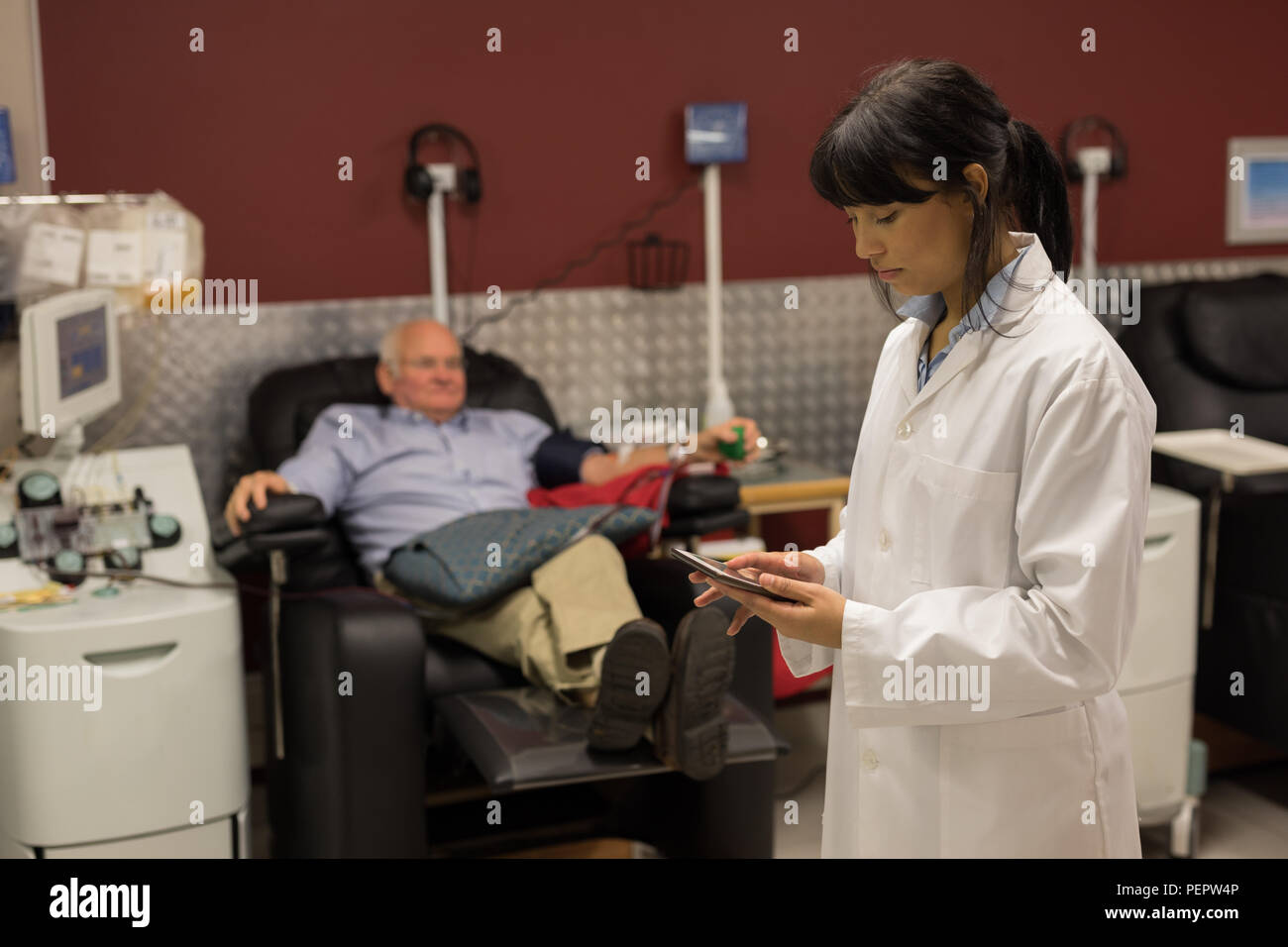 Physician using digital tablet while senior man donating blood Stock Photo