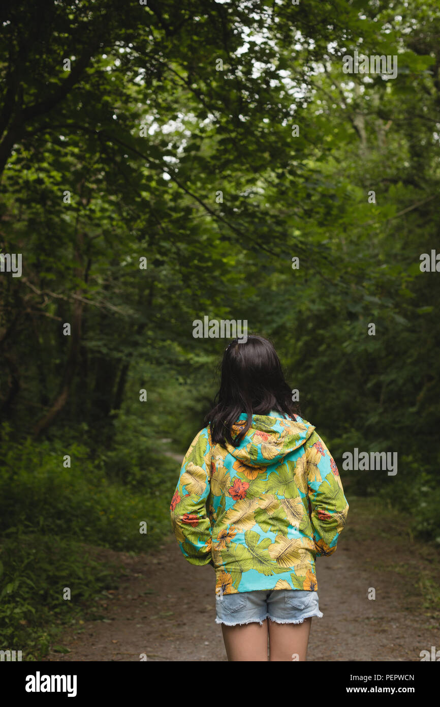 Girl standing alone in forest path Stock Photo