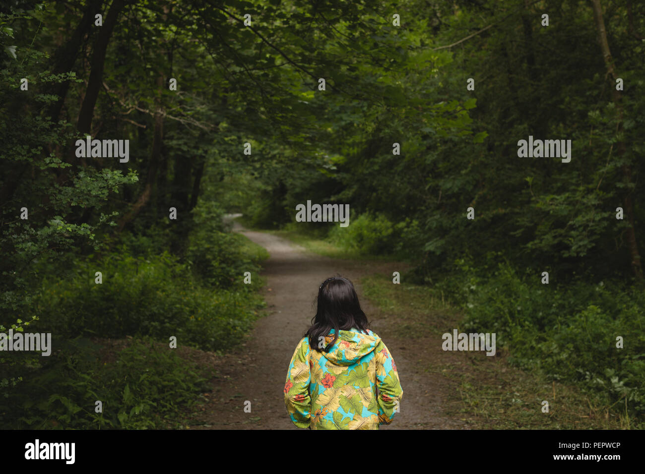 Girl standing alone in forest path Stock Photo