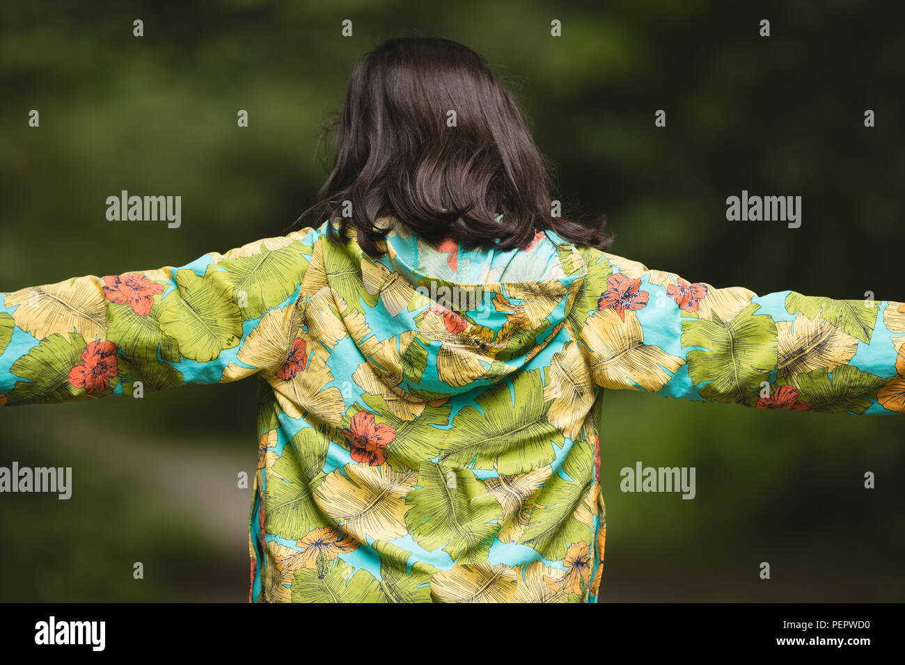 Girl with arms standing in forest Stock Photo
