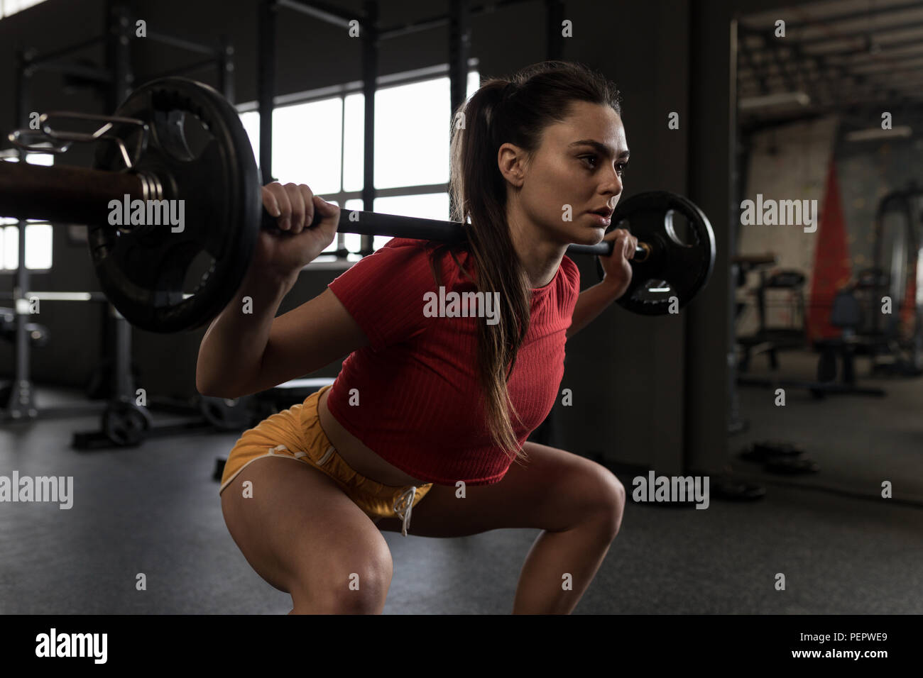 Woman doing a barbell squat in fitness studio Stock Photo