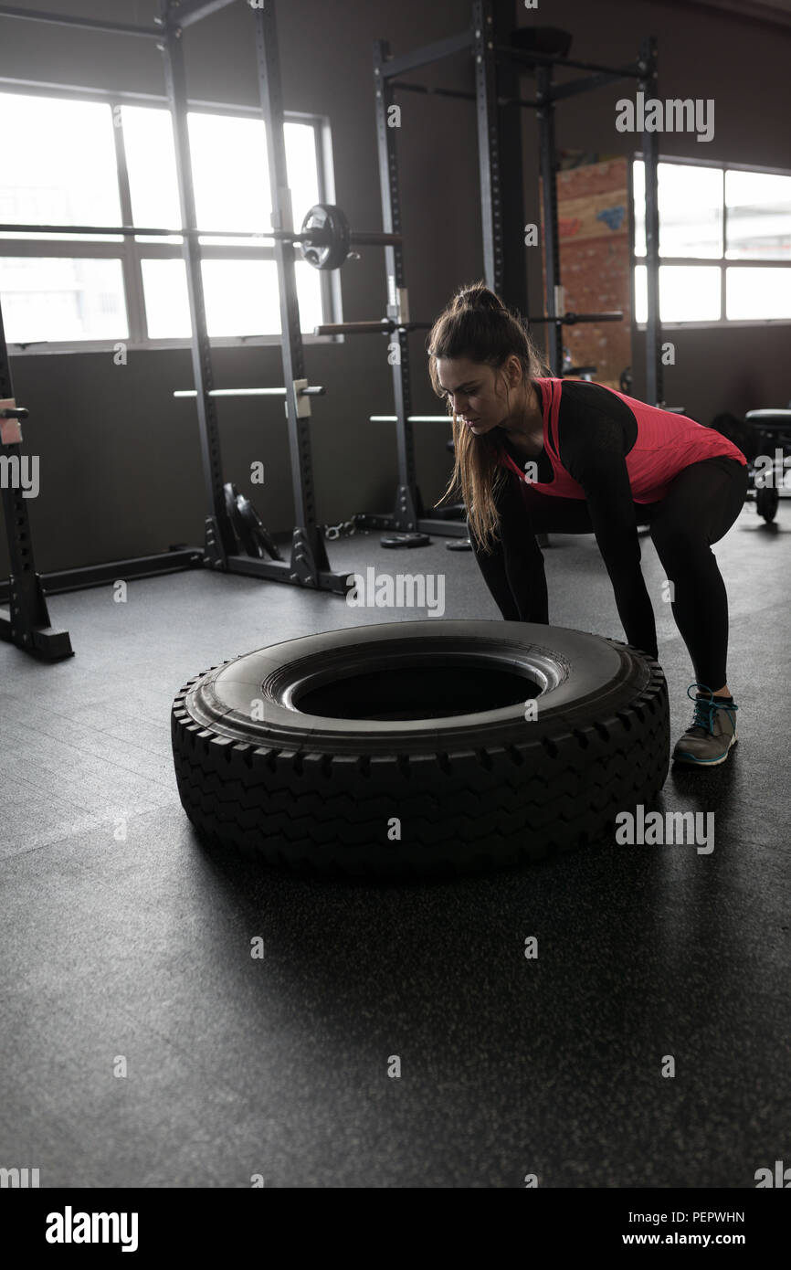 Woman exercising with tyre in fitness studio Stock Photo
