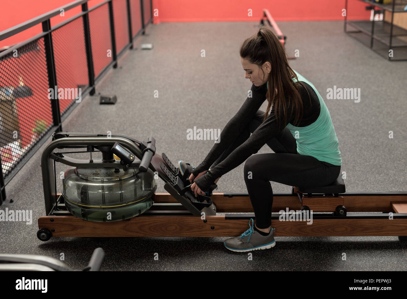 Woman using rowing machine in fitness studio Stock Photo