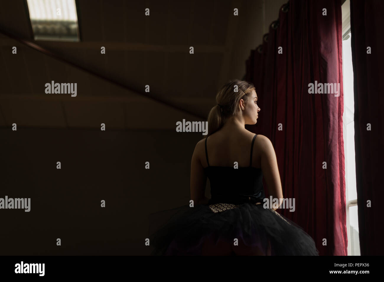 Thoughtful ballerina looking through window Stock Photo
