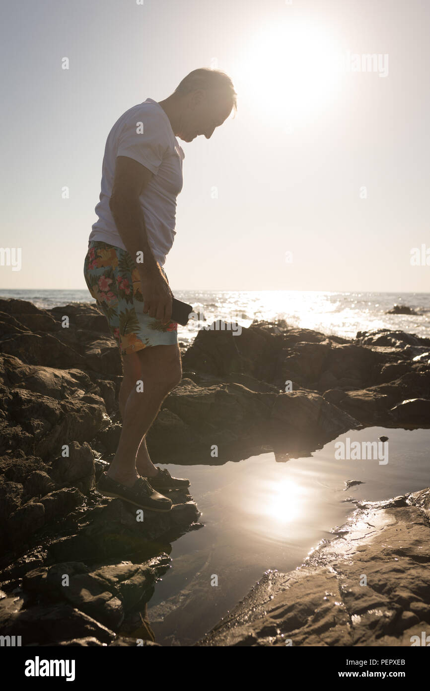 Senior man standing on rock near sea side Stock Photo