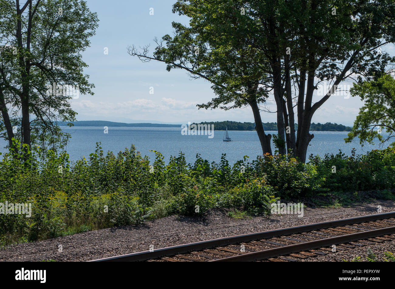 Railroad tracks on the edge of Lake Champlain with trees and crushed stone Stock Photo