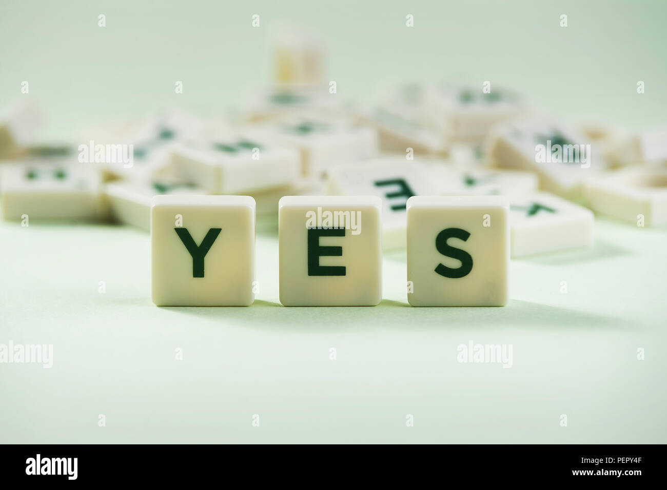 The word YES on pastel background, spelt with letter scrabble tiles