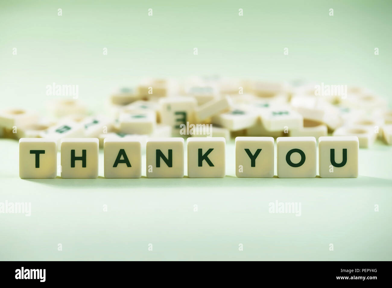 The word THANK YOU on pastel background, spelt with scrabble tiles