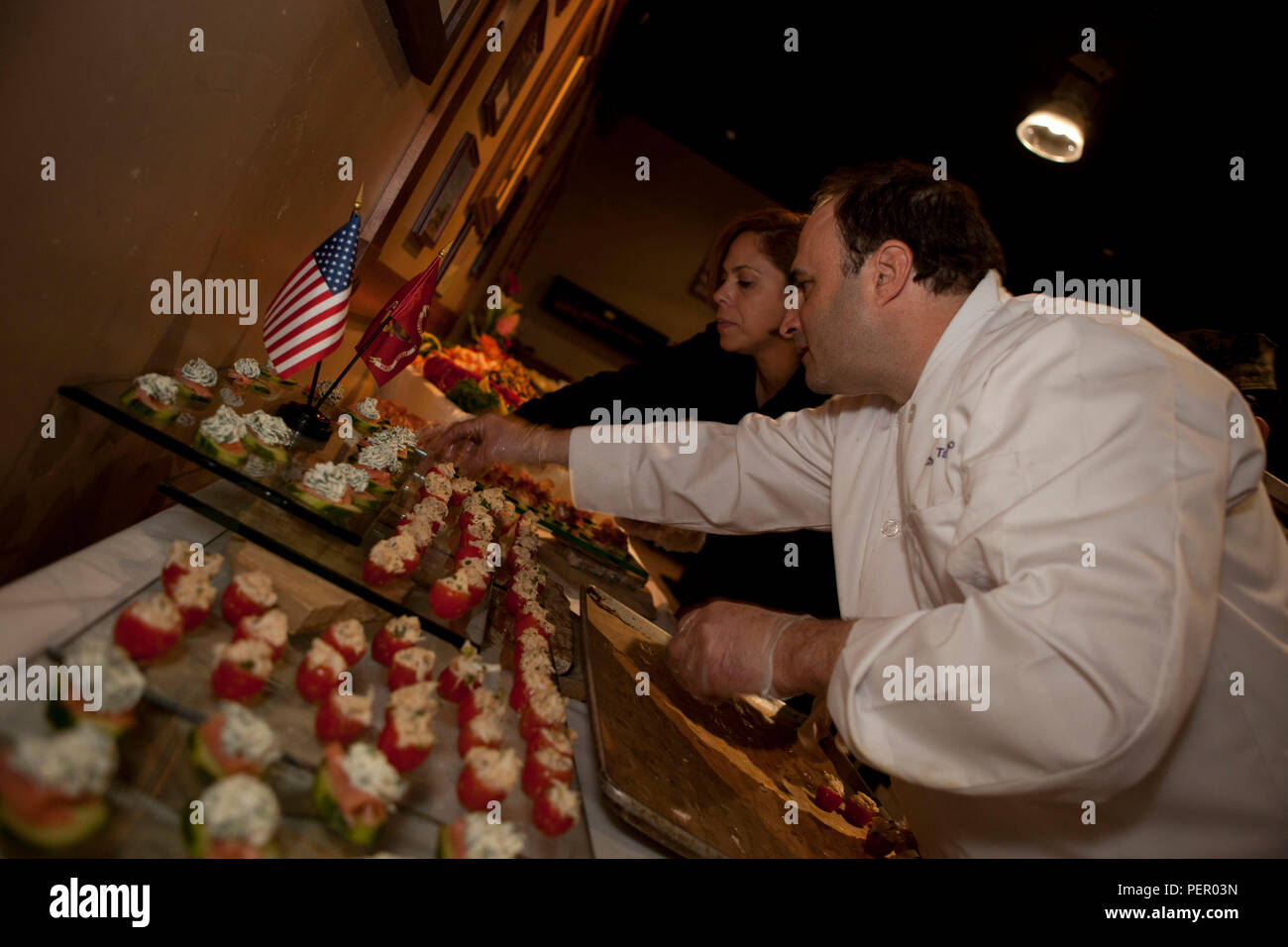 Celebrity head chef Rick Tarantino (right) places appetizers on a table at Iron Mike’s lounge on Camp Pendleton, Calif., prior to the start of the Food Industry Feeding Heroes (FISH) dinner, Jan. 21, 2016. The event is hosted by Camp Pendleton and MCIWEST Commanding General, Brig. Gen. Edward Banta, and Mr. Paul Chapa to honor service members for their accomplishments and sacrifices. (U.S. Marine Corps photo by Cpl. Brian Bekkala/MCIWEST-MCB CamPen Combat Camera/Released) Stock Photo