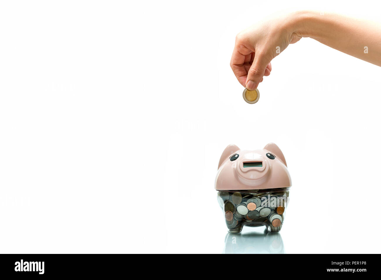 Hand putting a coin into piggy bank isolated in white background Stock ...