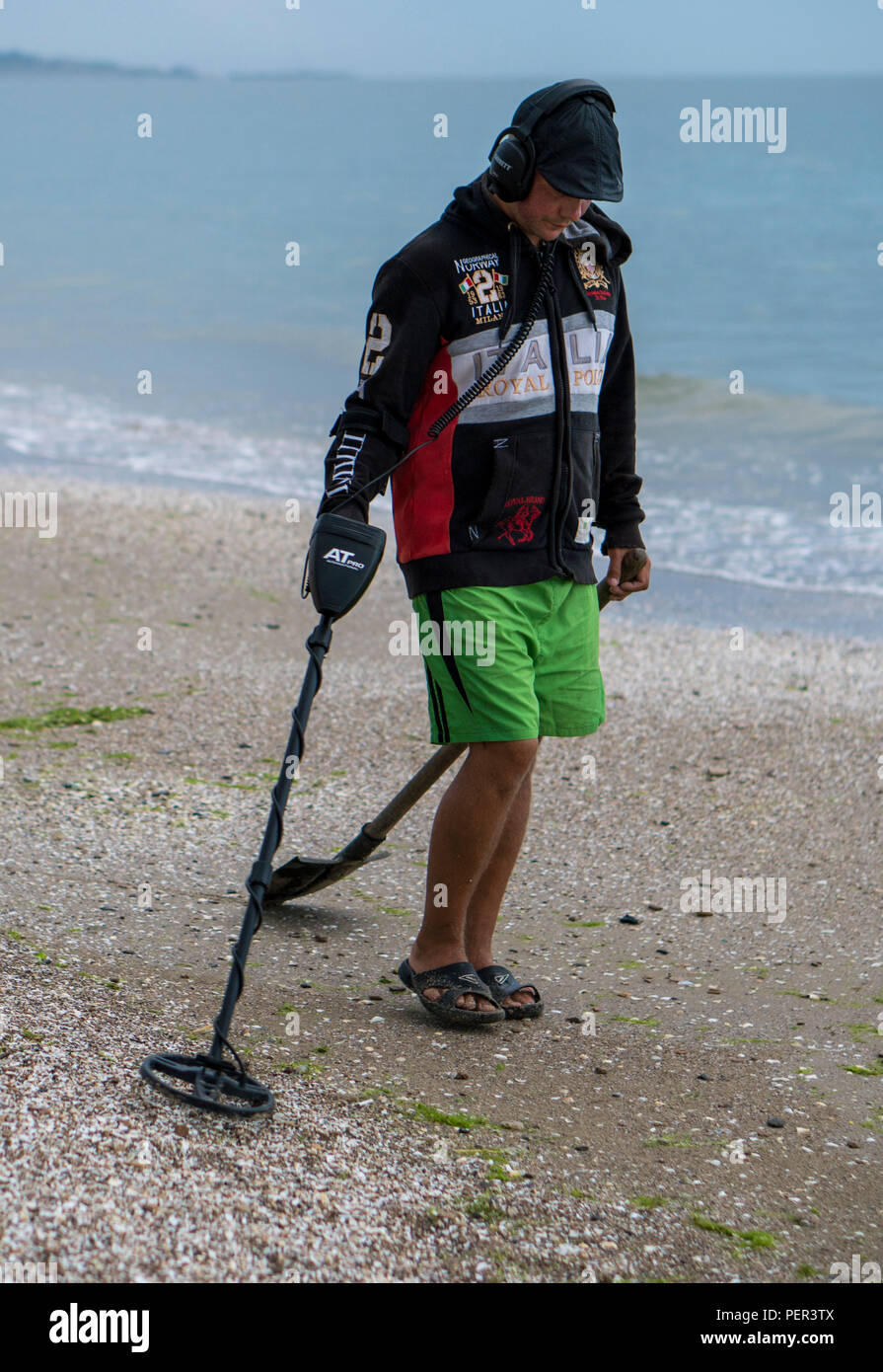 Man in headphones searching for a precious metal using a metal detector ...