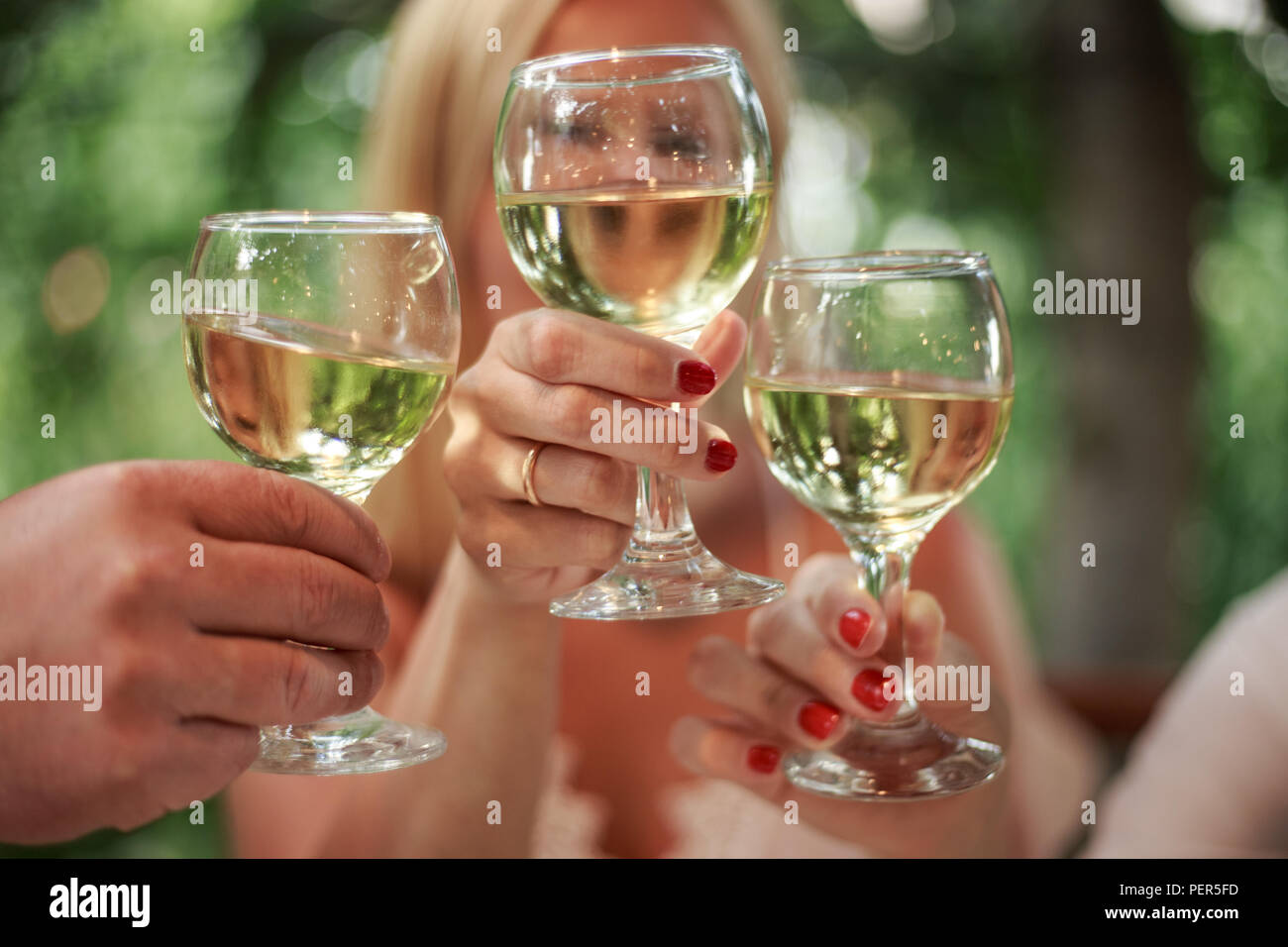 Closeup photo of hands clinking glasses with white wine Stock Photo