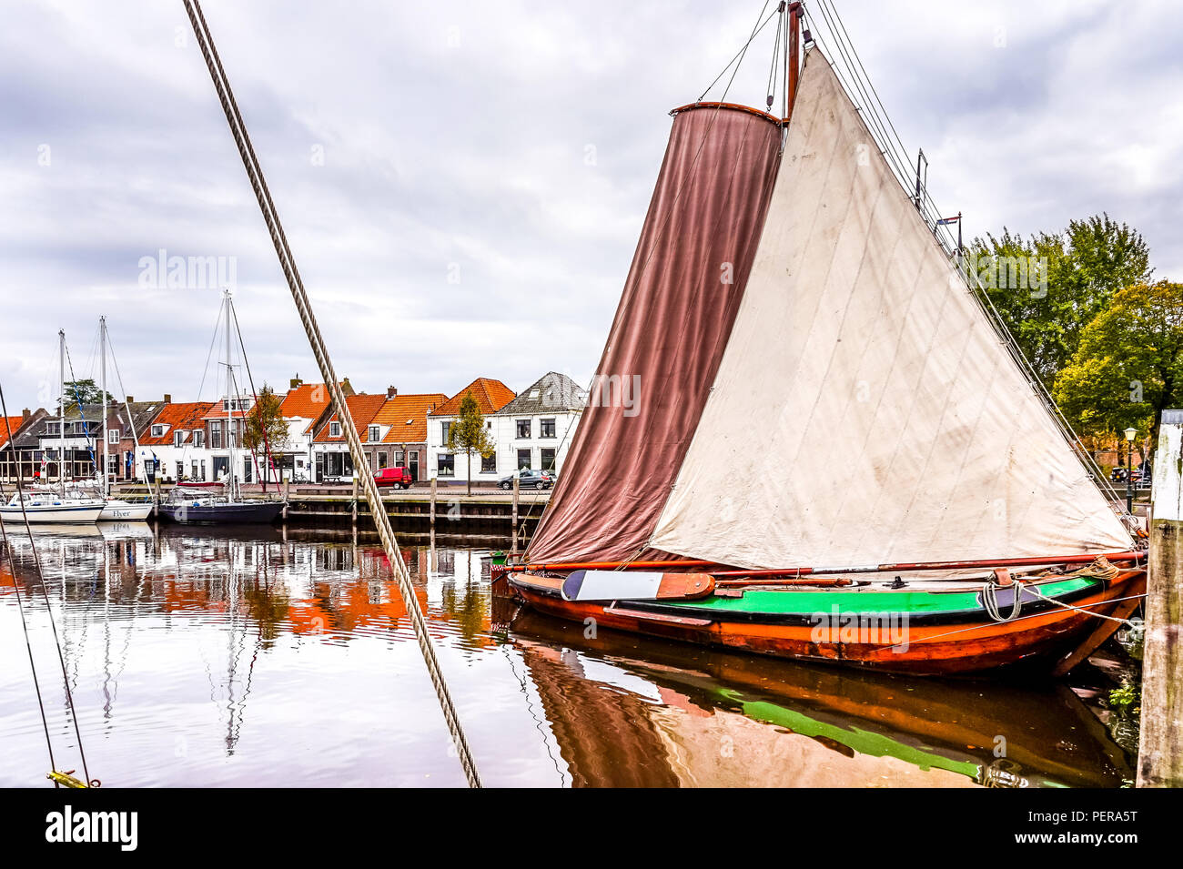 A flat bottom 'Botter' ship in full sail in the harbor of the historic and touristic Dutch fishing village of Elburg along the Ijsselmeer Stock Photo