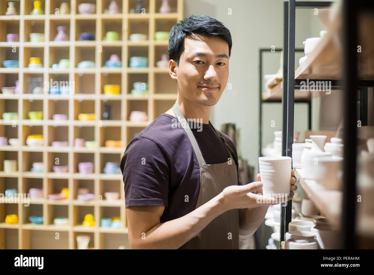 Young potter showing pottery in studio Stock Photo