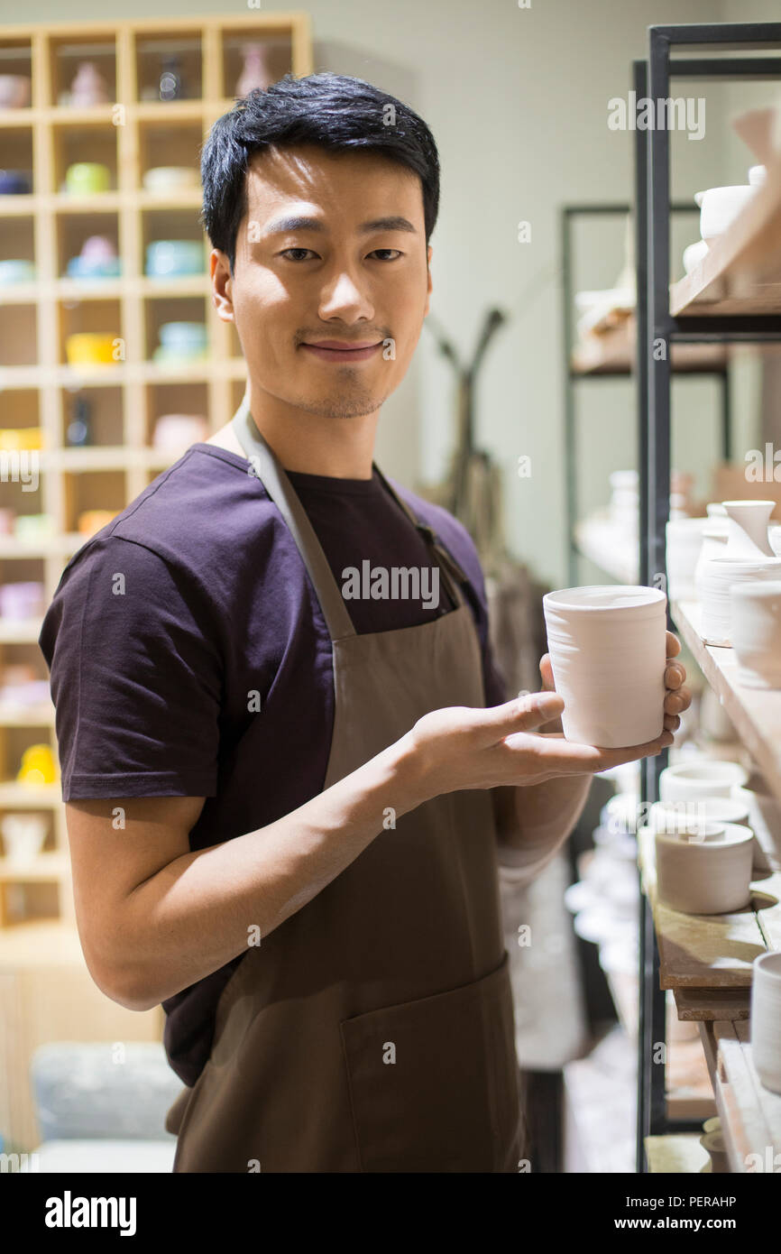 Young potter showing pottery in studio Stock Photo