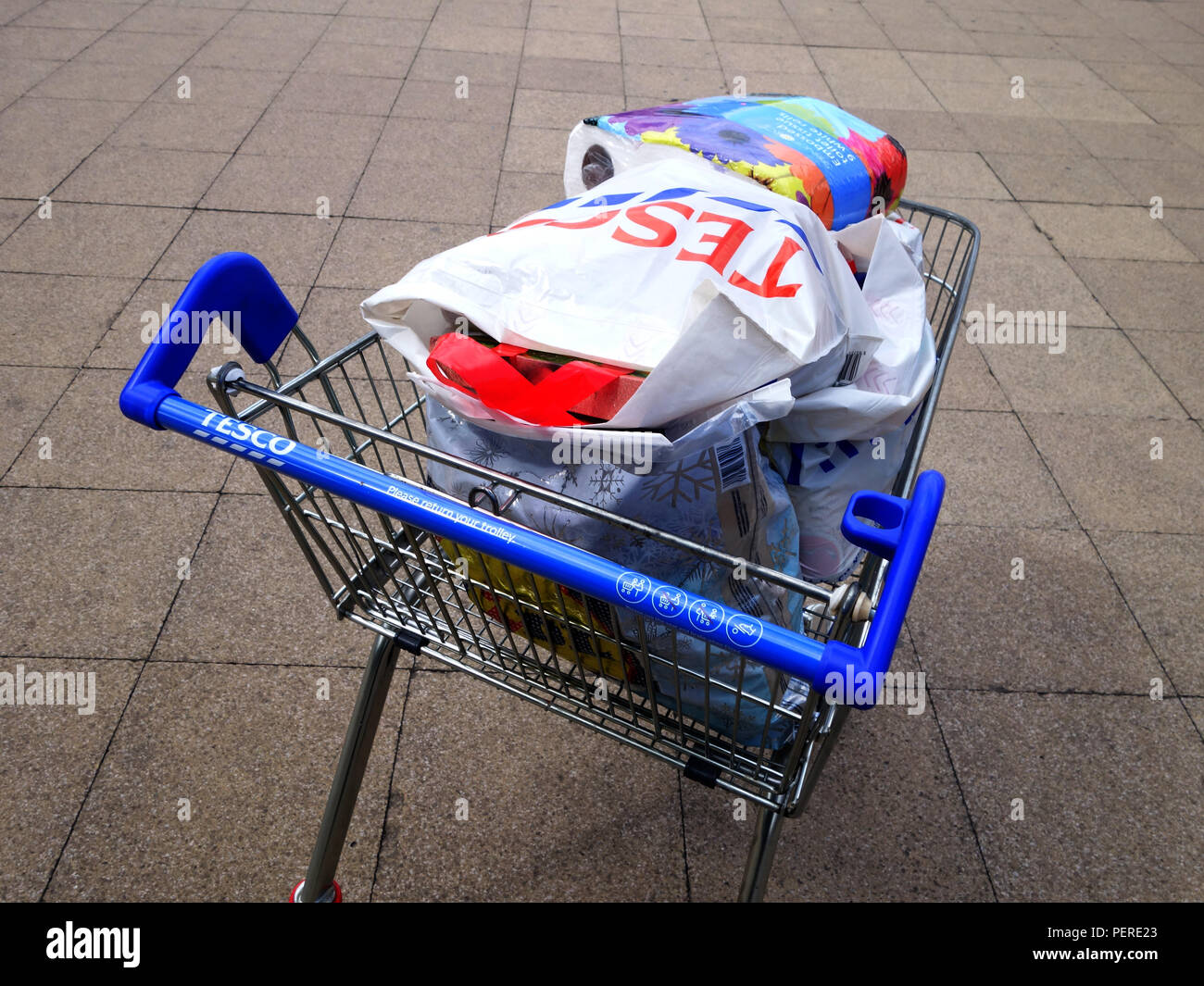 Full Supermarket trolly. Full with groceries in a tesco bag piled high in a Tesco  bag shopping trolley being pushed across paved area to the car park Stock  Photo - Alamy
