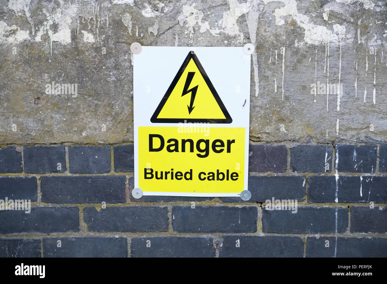 Buried electrical cable danger on wall Stock Photo