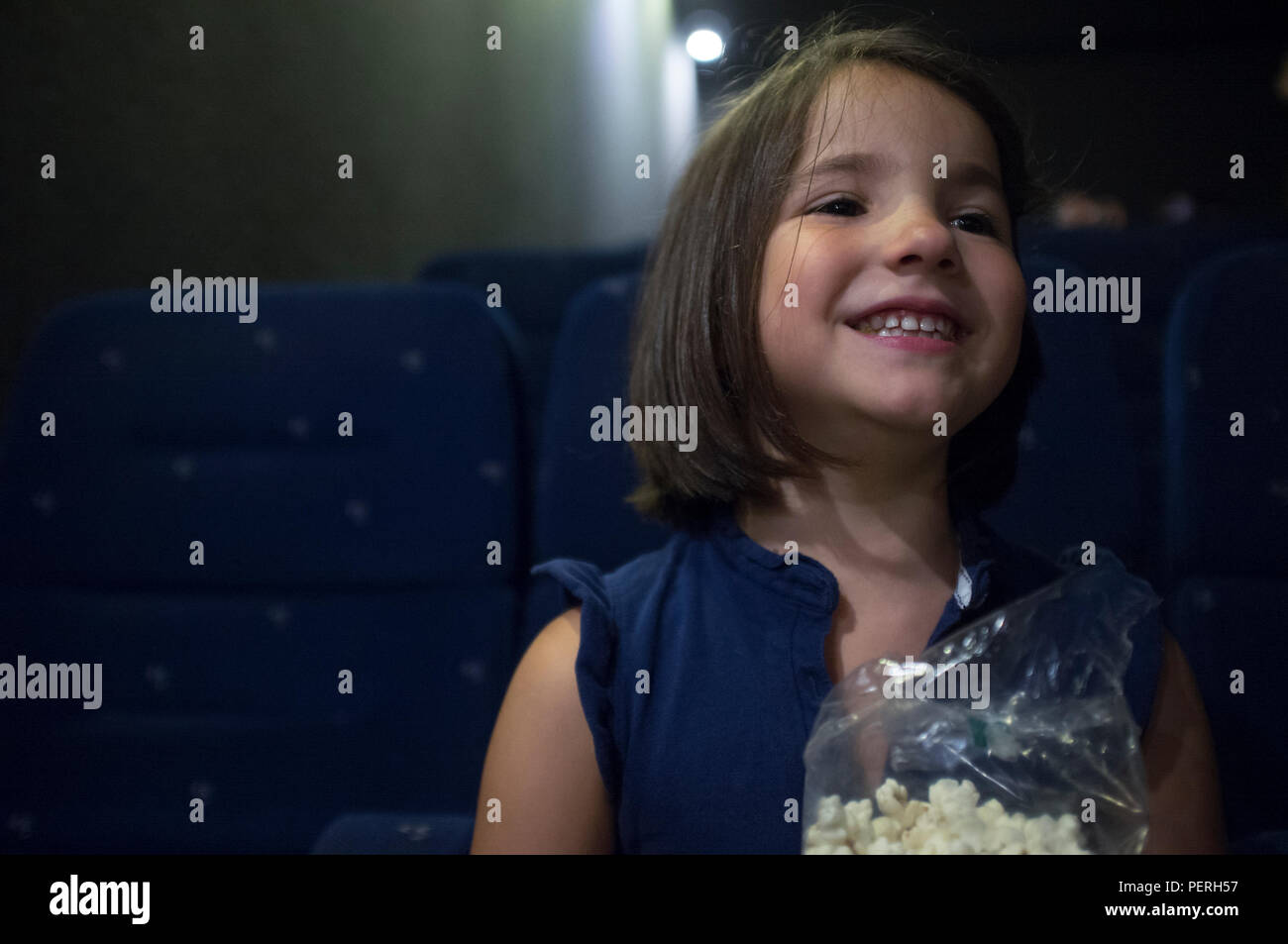 Child girl watching film at real cinema. She is got a happy expression Stock Photo