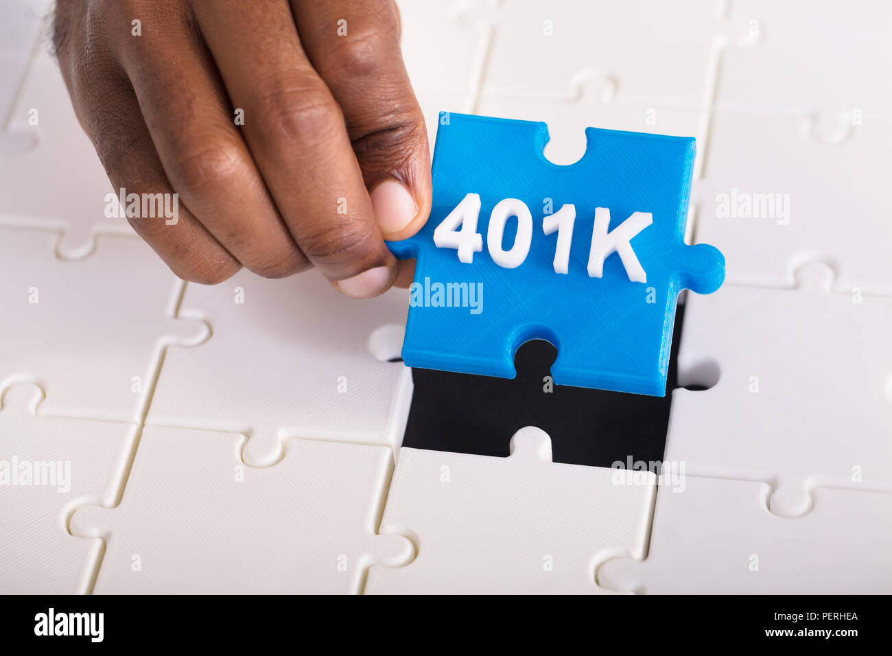 Overhead View Of A Person's Hand Holding 401k Blue Jigsaw Puzzle Stock Photo