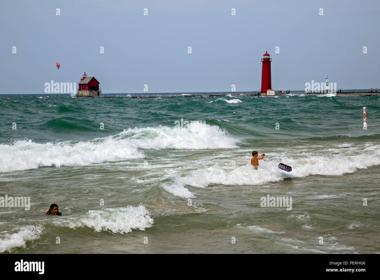 Young boy with boogie board, trying to swim in Lake Michigan when there are big waves. Stock Photo