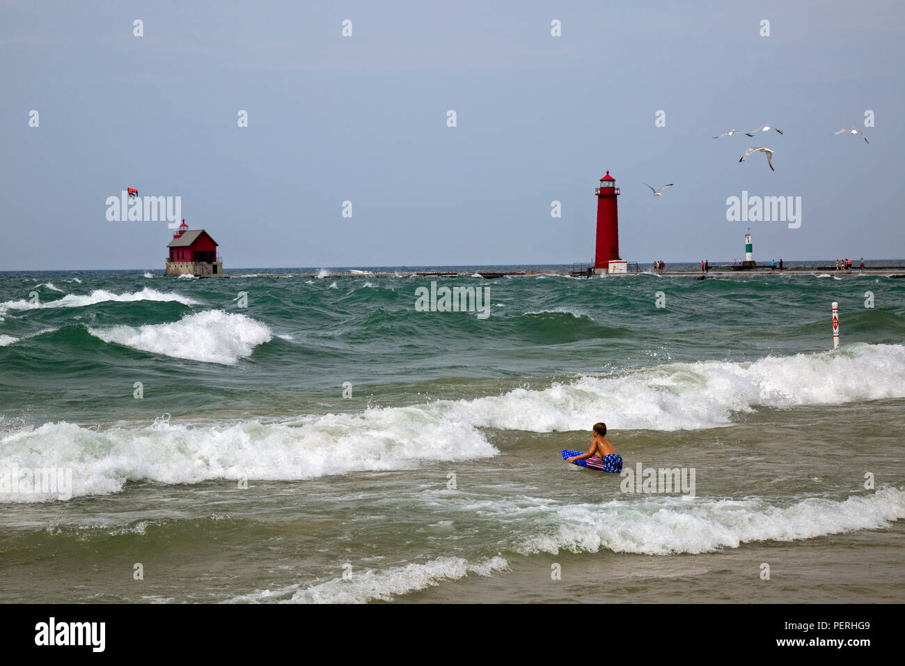 Young boy with boogie board, trying to swim in Lake Michigan when there are big waves. Stock Photo
