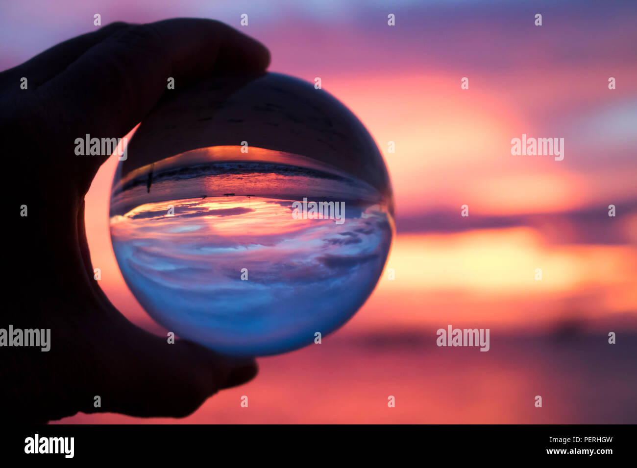 Pink and purple sunset over ocean taken through glass ball Stock Photo ...