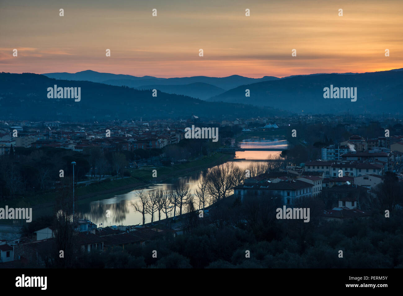 The sun rises over the River Arno and the suburbs of Florence, with the Fiesolean Hills providing a backdrop. Stock Photo