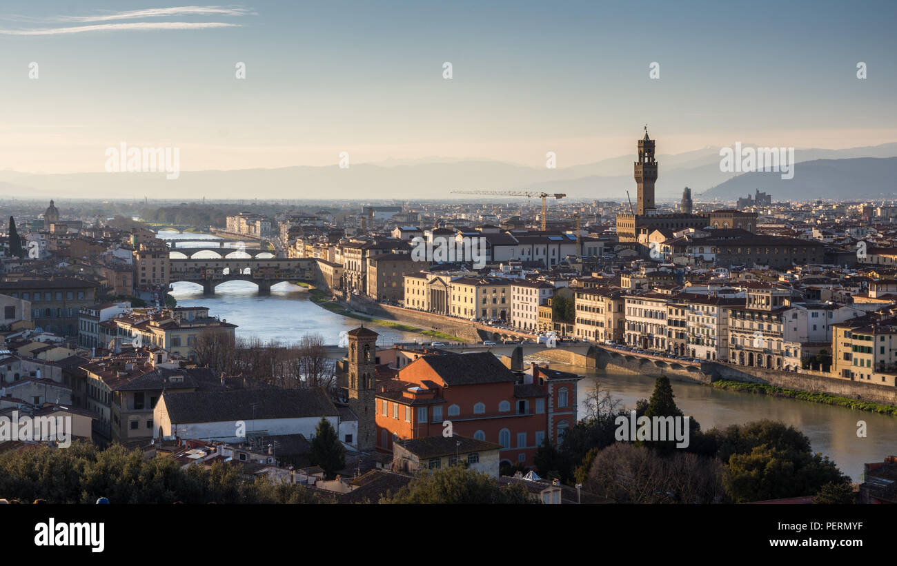 Florence, Italy - March 23, 2018: Evening light illuminates the cityscape of Florence along the Arno River, including the landmark Ponte Vecchio bridg Stock Photo