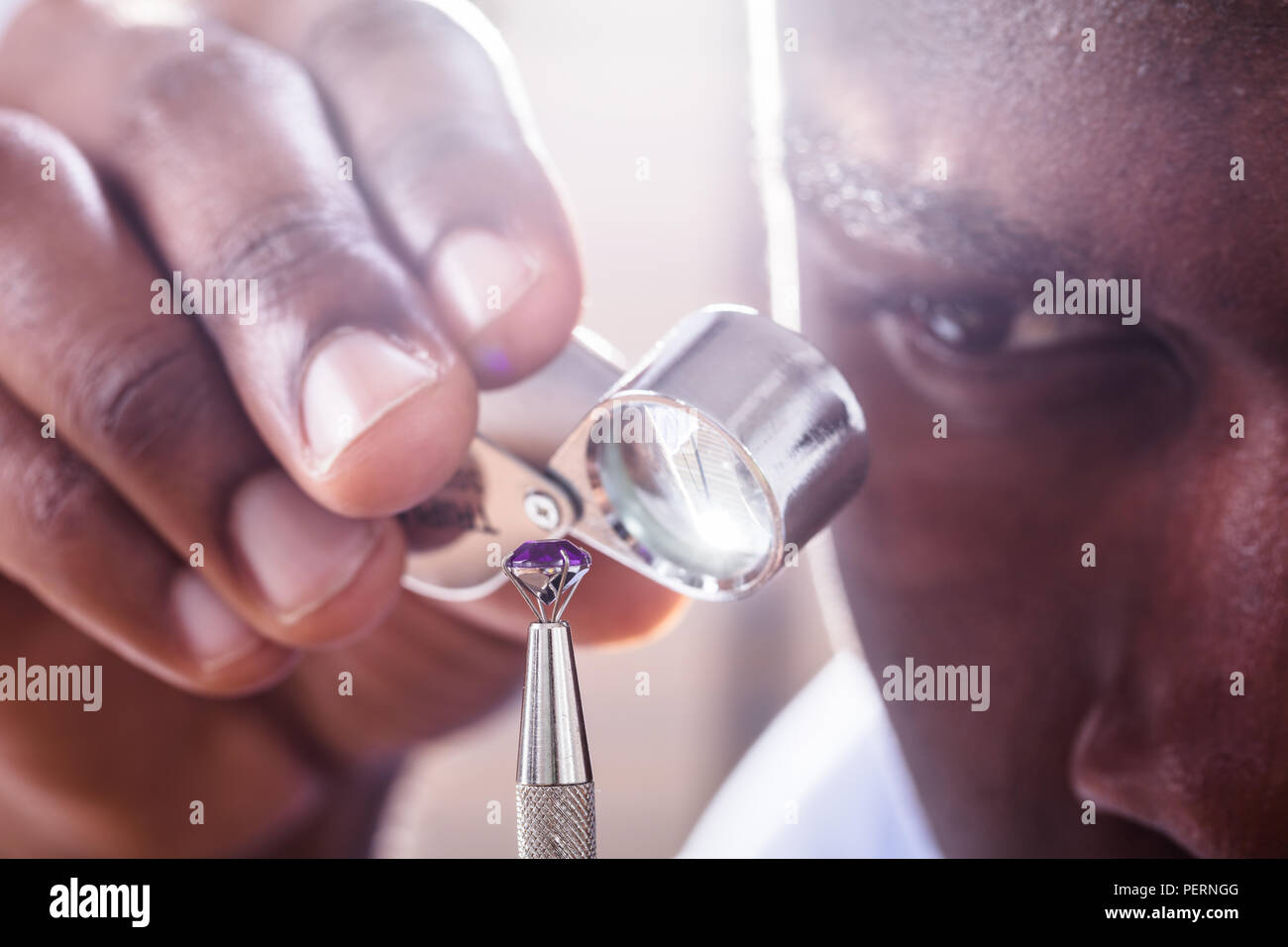 Close-up Of Jeweler Examining Diamond Through Loupe Stock Photo