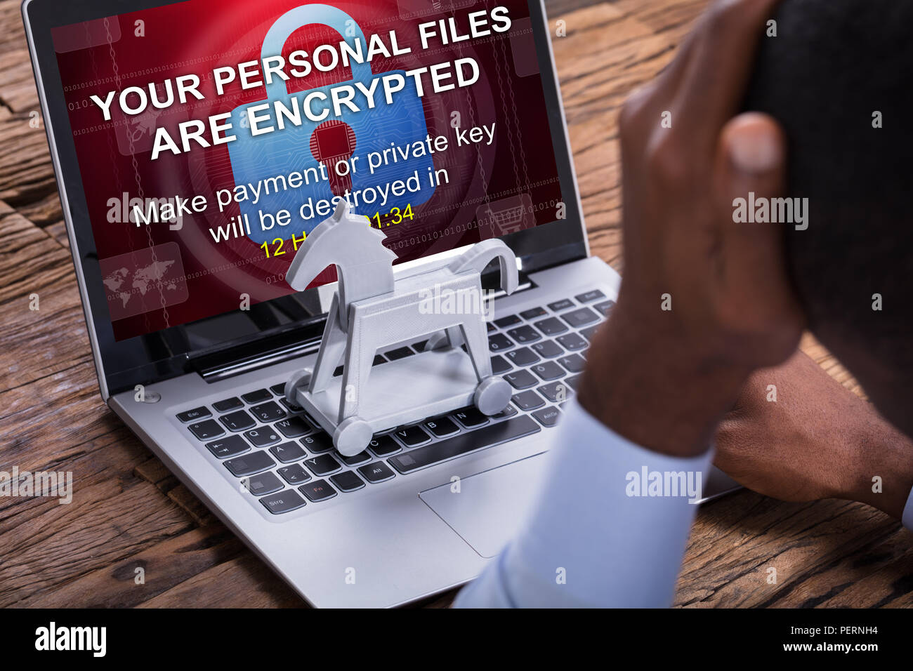 Close-up Of Worried Businessman Encrypted Text On The Laptop Over The Wooden Desk Stock Photo