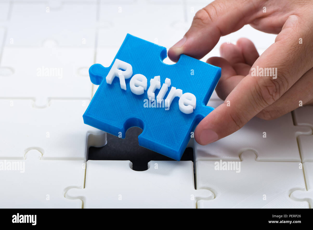 Close-up of a person placing last blue retire piece into jigsaw puzzle Stock Photo