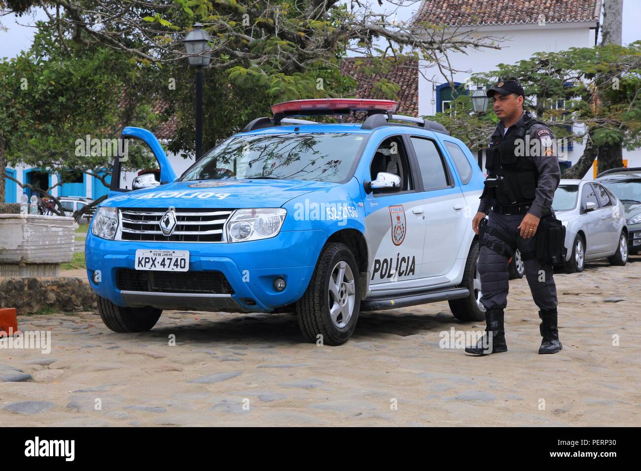 PARATY, BRAZIL - OCTOBER 14, 2014: Police officer walks next to Renault Duster police car in Paraty (state of Rio de Janeiro). PMERJ state police empl Stock Photo