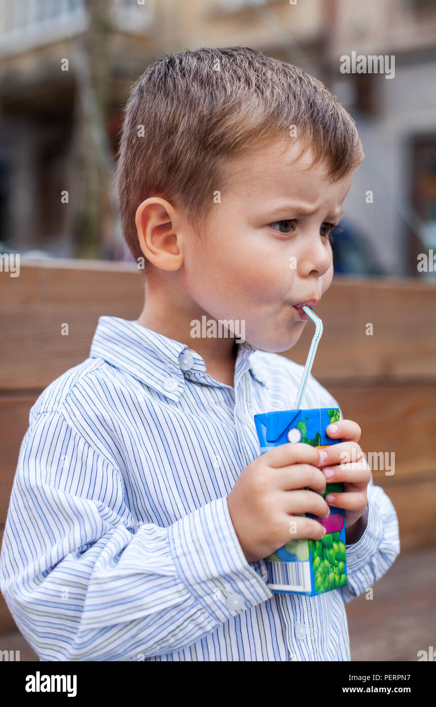 Lovely kid drinking juice from straw. Cute little boy drinking a Juice