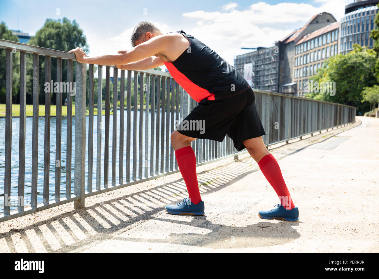 Side View Of A Man Doing Push-Ups On Railing At Outdoors Stock Photo