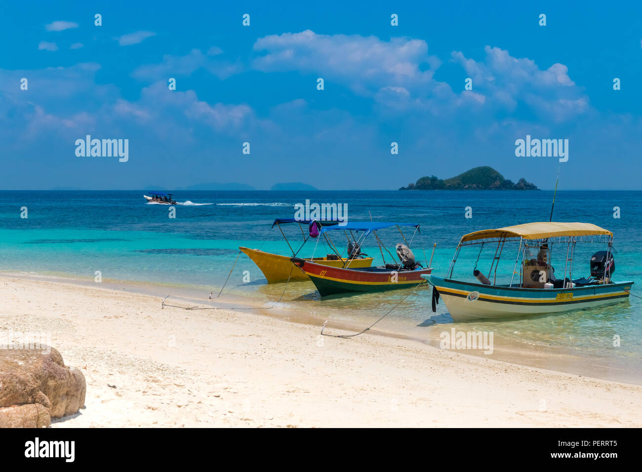 Tourist boats are anchored on the lovely white fine sandy beach of the uninhabited Rawa Island next to Perhentian Kecil in Malaysia. On the azure blue... Stock Photo