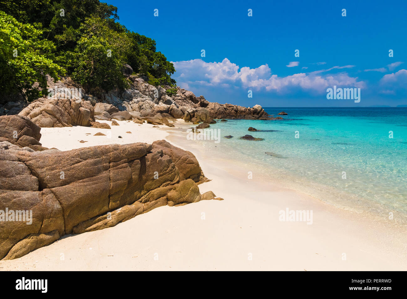 Beautiful stretch of a fine soft white sandy beach, turquoise blue shimmering water, big rocks & lush trees which belongs to Rawa Island, a popular... Stock Photo