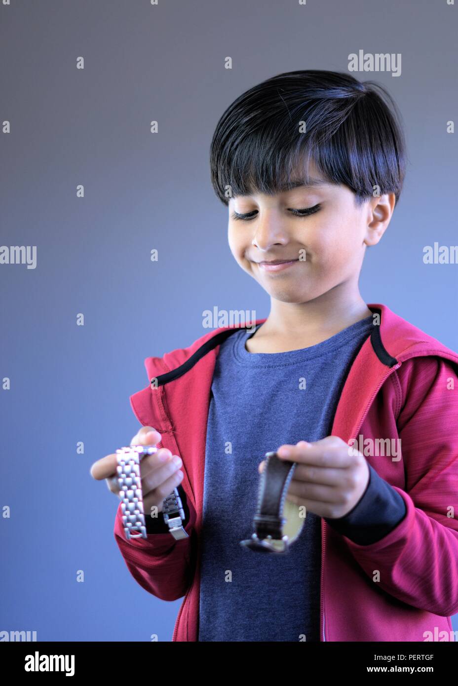 Looking at time. Smiling child holding wrist watches. Kid holding two wrist watches. Stock Photo