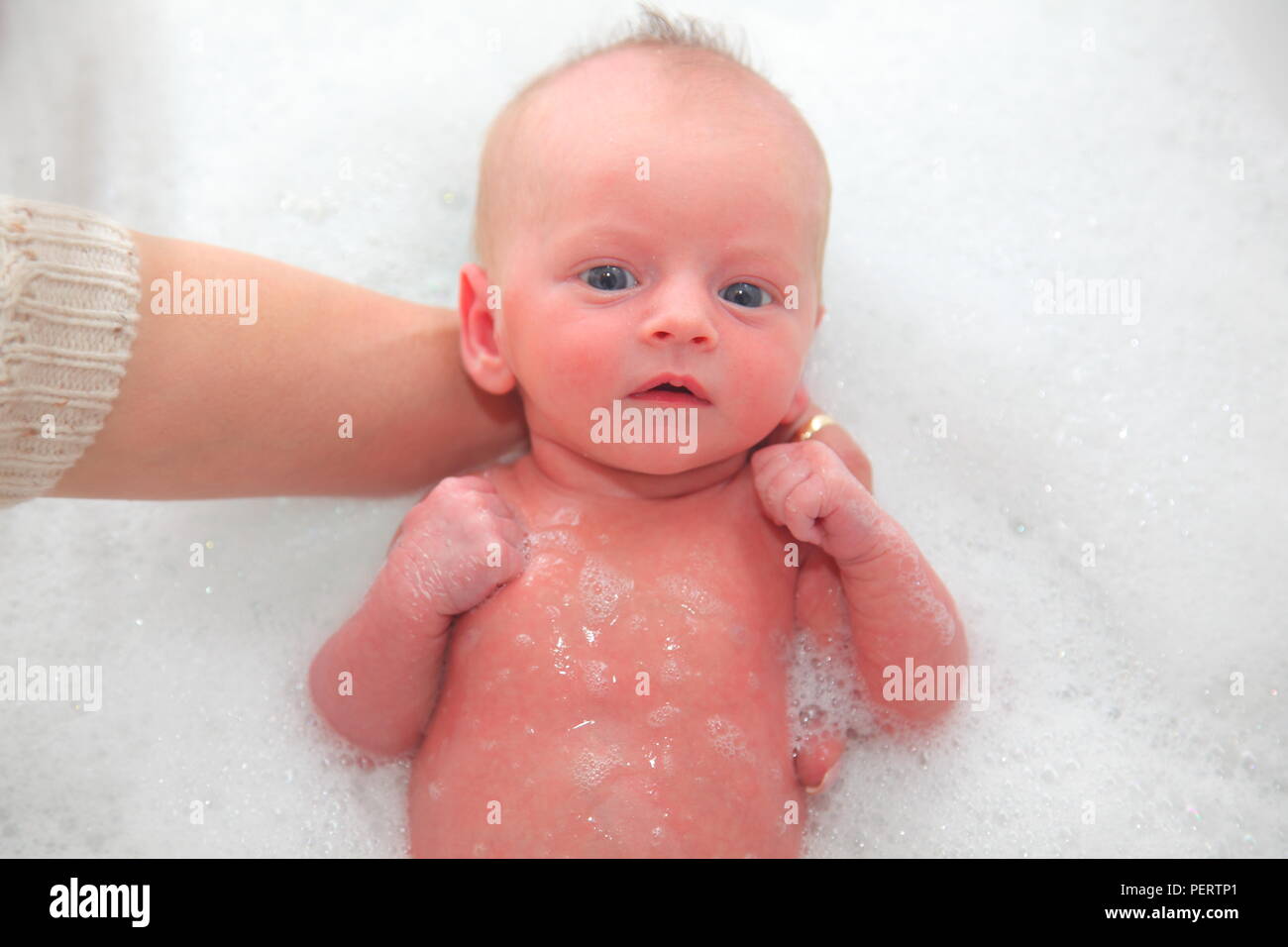 A newborn baby has a bath for the first time a few days after being born. Stock Photo