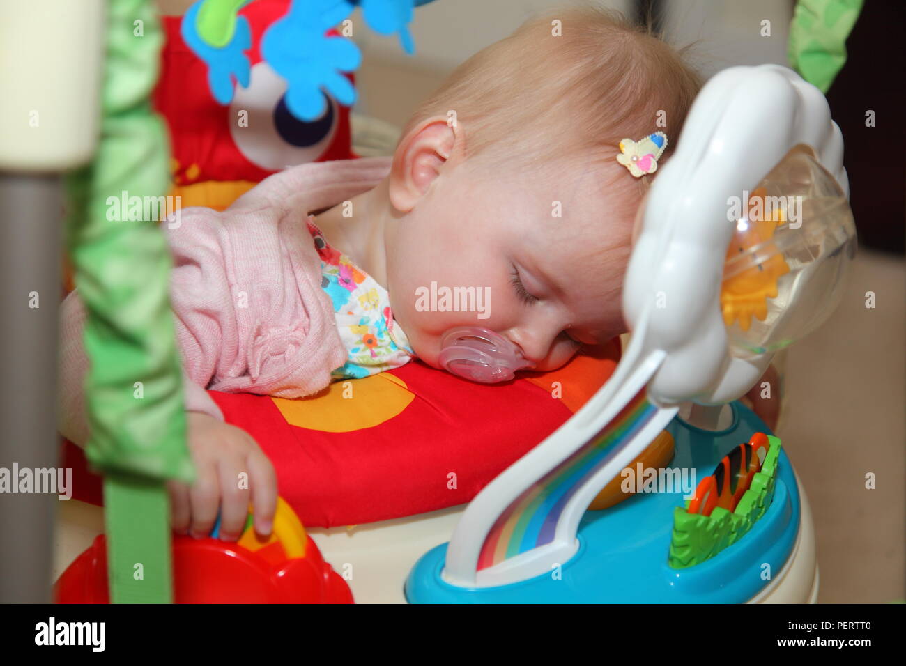 8 month old baby girl falls asleep on her baby bouncer. while playing Stock Photo