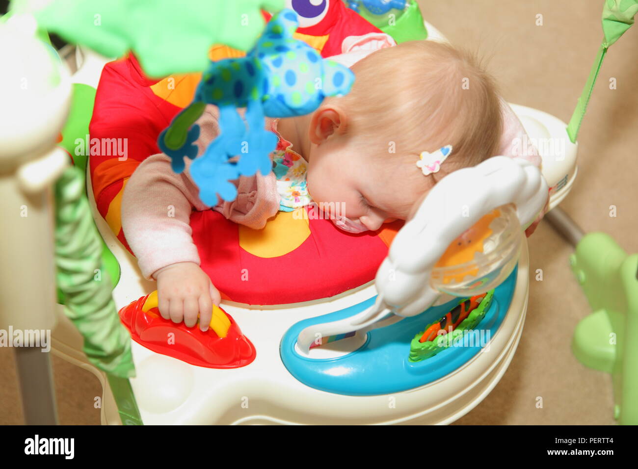 8 month old baby girl falls asleep on her baby bouncer. while playing Stock Photo